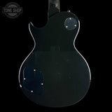The back view of a black electric guitar, showing the glossy finish and body contours against a black background, with a Tone Shop watermark in the top left corner.