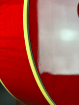 Close-up of a glossy red guitar body with a yellow binding edge and dark striping.