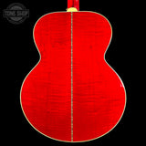 The back of a double-cutaway acoustic guitar with a vibrant red flamed maple top, a gold-toned binding, and a gold-toned center stripe down the middle, shown against a solid black background.