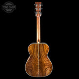 Back view of a wooden acoustic guitar on a black background with 'Tone Shop' logo.