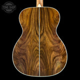 Close-up of a wooden acoustic guitar back with 'Tone Shop' logo.