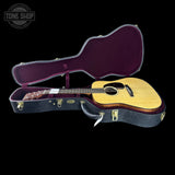 Acoustic guitar in an open case with 'Tone Shop' logo in the corner.
