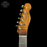 Close-up of the headstock of a Fender Custom '50 style electric guitar against a solid black background, showing the wood grain and tuning pegs.