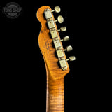 Close-up of the headstock of an electric guitar with a natural flamed maple wood finish and gold-toned tuning pegs, shown against a solid black background.