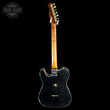 A used Fender Telecaster electric guitar shown from the back, featuring a black body with visible wear, scuffs, and gold hardware, set against a solid black background.