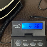 A close-up of a smart weigh ACE110 digital scale showing a weight of 6.6 lbs (30 lbs) on its blue backlit display, placed on a dark wooden table next to a coiled cable.