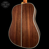 Back view of a wooden acoustic guitar with 'Tone Shop' logo.