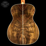 Close-up of a wooden acoustic guitar body with 'Tone Shop' logo.