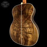 Close-up of a wooden acoustic guitar with a visible brand logo in the corner.