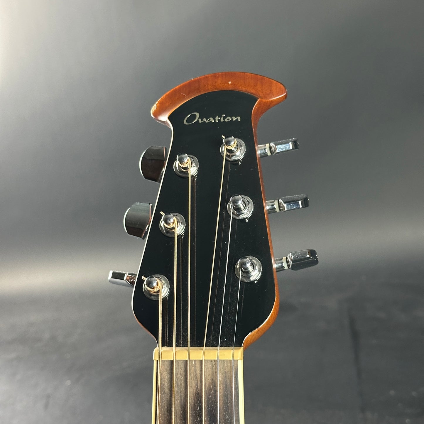 Guitar headstock with 'Ovation' branding on a gray background