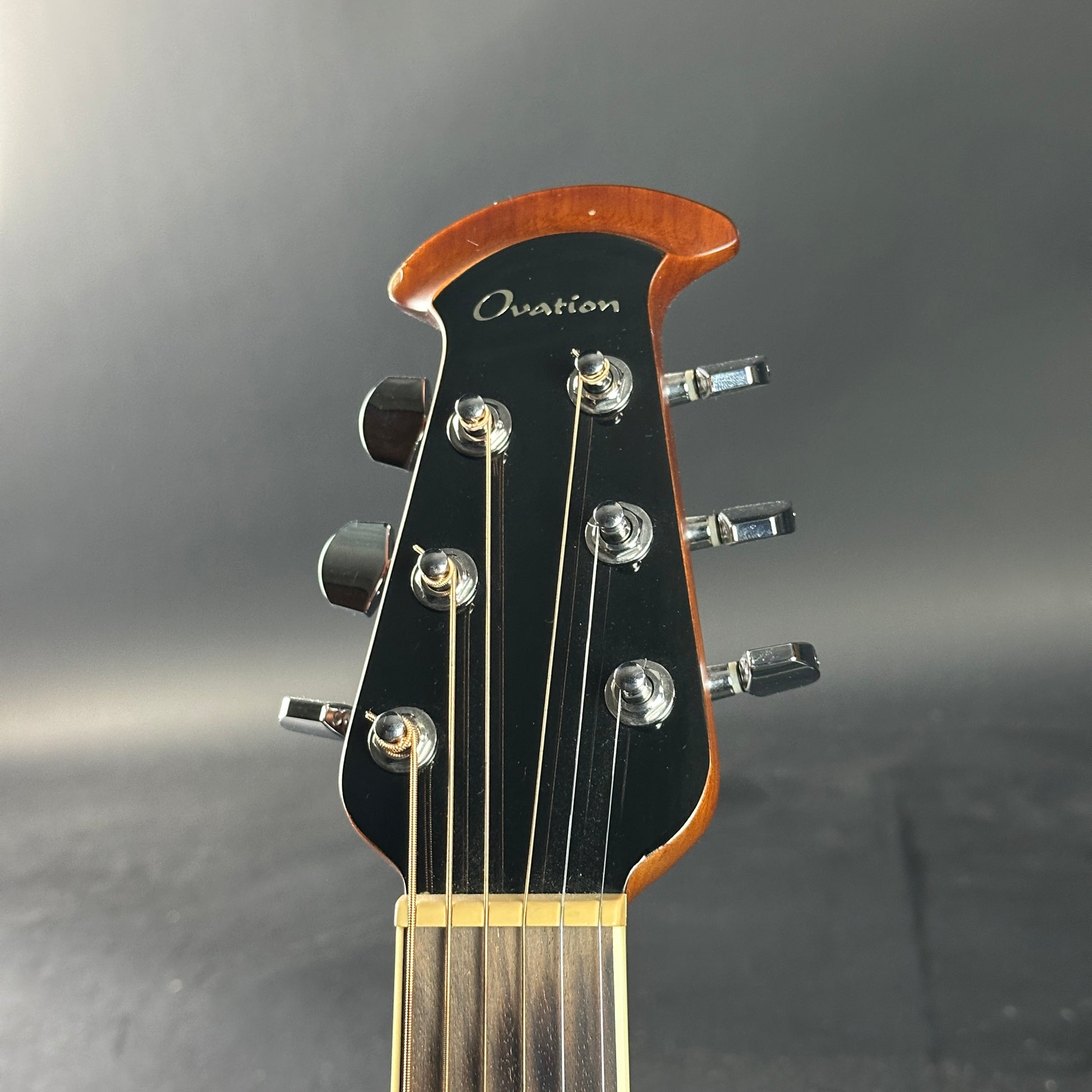 Guitar headstock with 'Ovation' branding on a gray background