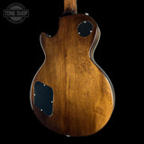 The back of an electric guitar with a glossy brown wood finish, featuring black pickguard plates and silver hardware, shown against a solid black background with a Tone Shop watermark in the top left.