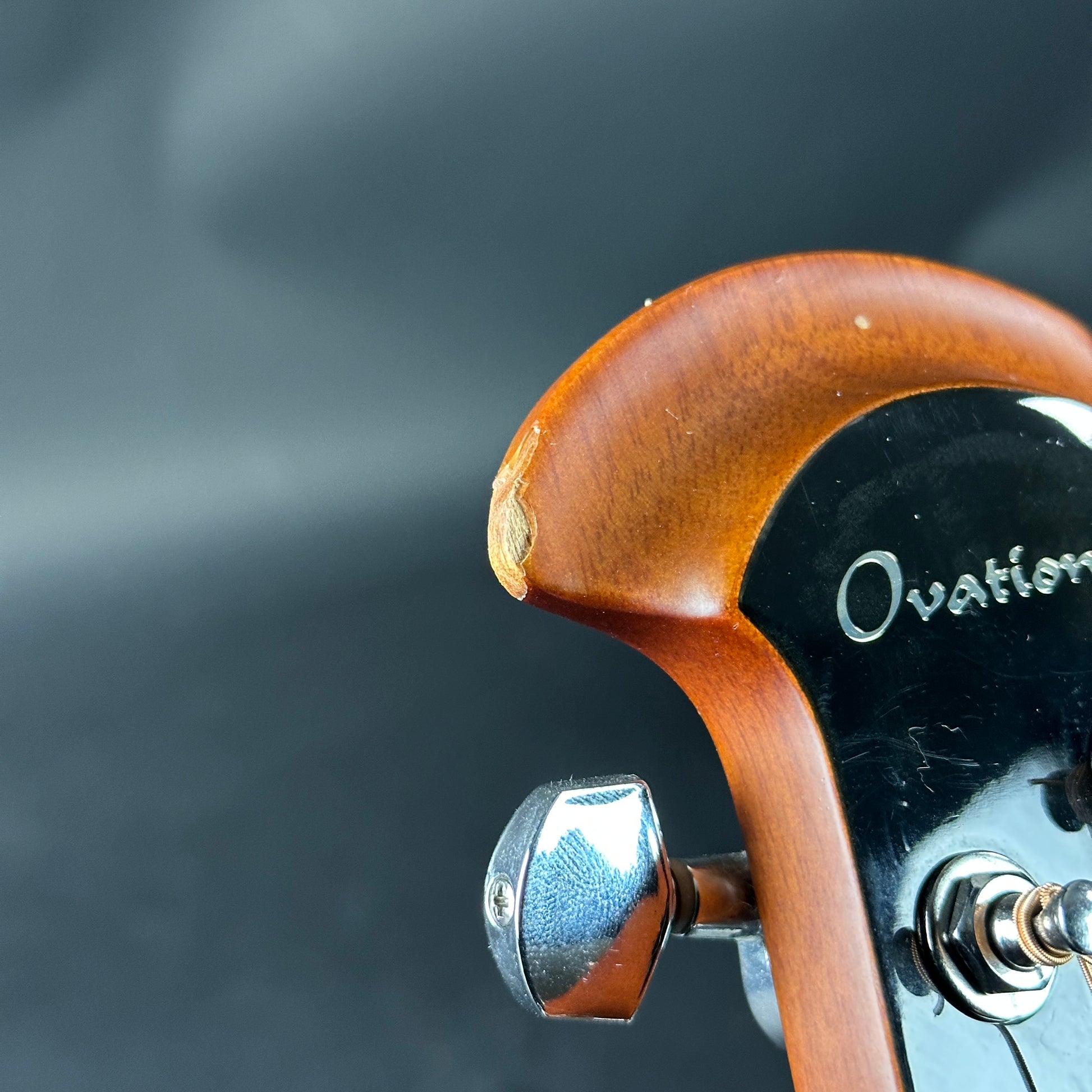 Close-up of a guitar headstock with 'Ovation' branding on a dark background