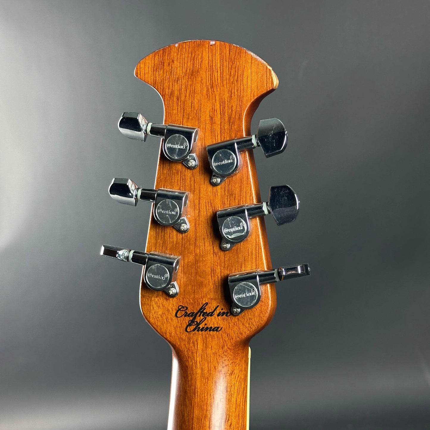 Guitar headstock with tuning pegs on a gray background