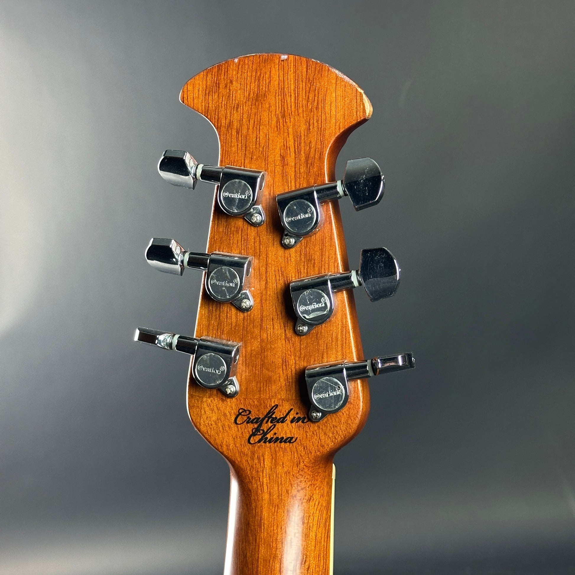 Guitar headstock with tuning pegs on a gray background