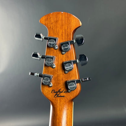 Guitar headstock with tuning pegs on a gray background