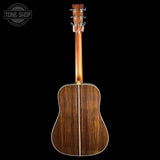 Acoustic guitar with a wooden finish on a black background, featuring the Tone Shop logo.