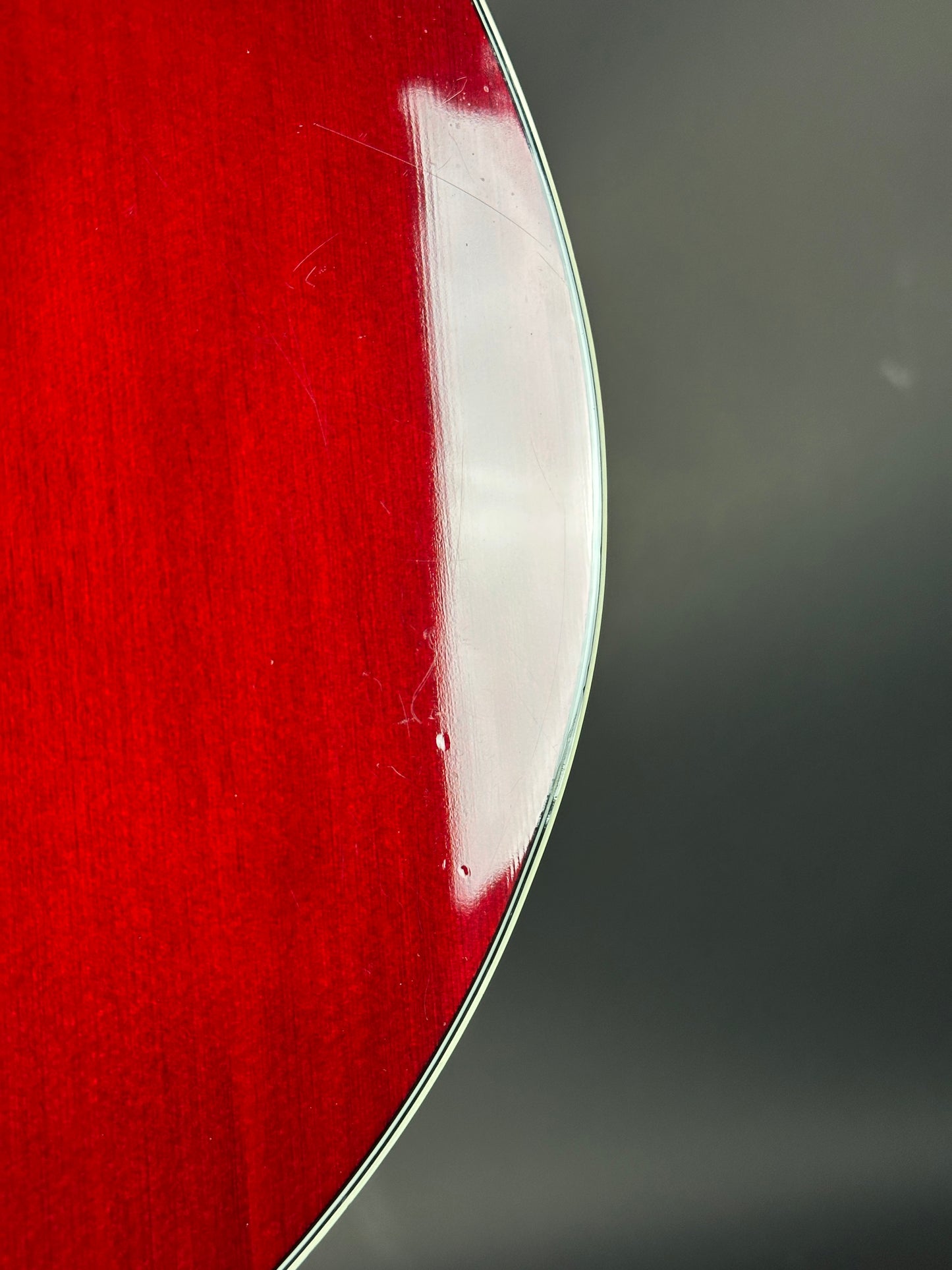 Close-up of a red guitar with a clear finish on a dark background