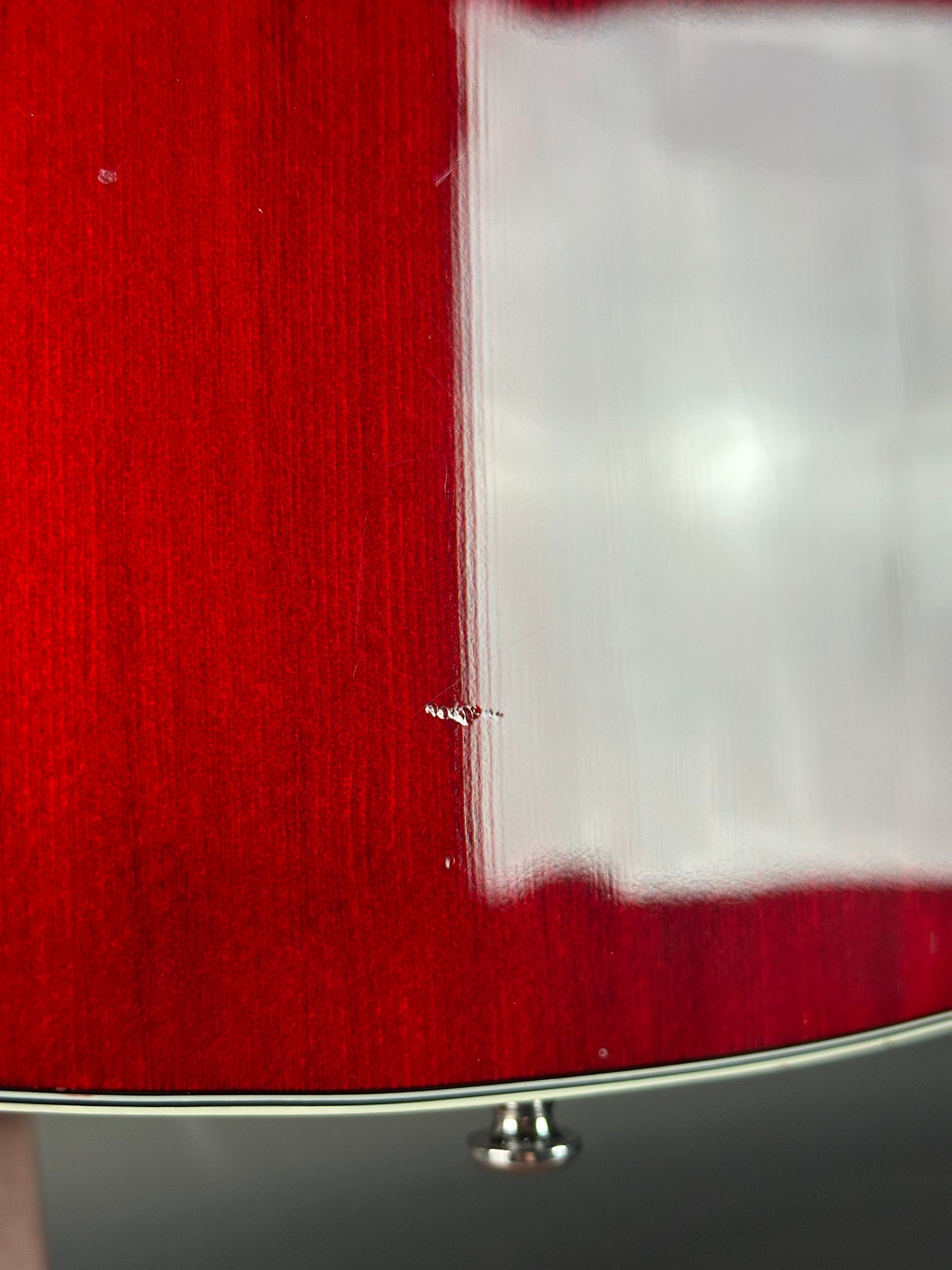 Close-up of a red guitar with a white pickguard