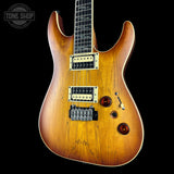 A double-cutaway electric guitar with a natural sunburst wood finish, featuring dual humbucker pickups, a black fretboard, and gold hardware, shown against a solid black background.