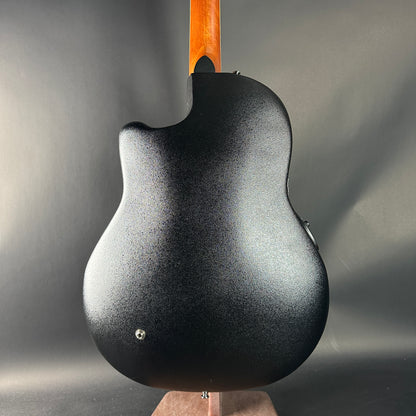Black electric guitar with a wooden neck on a gray background