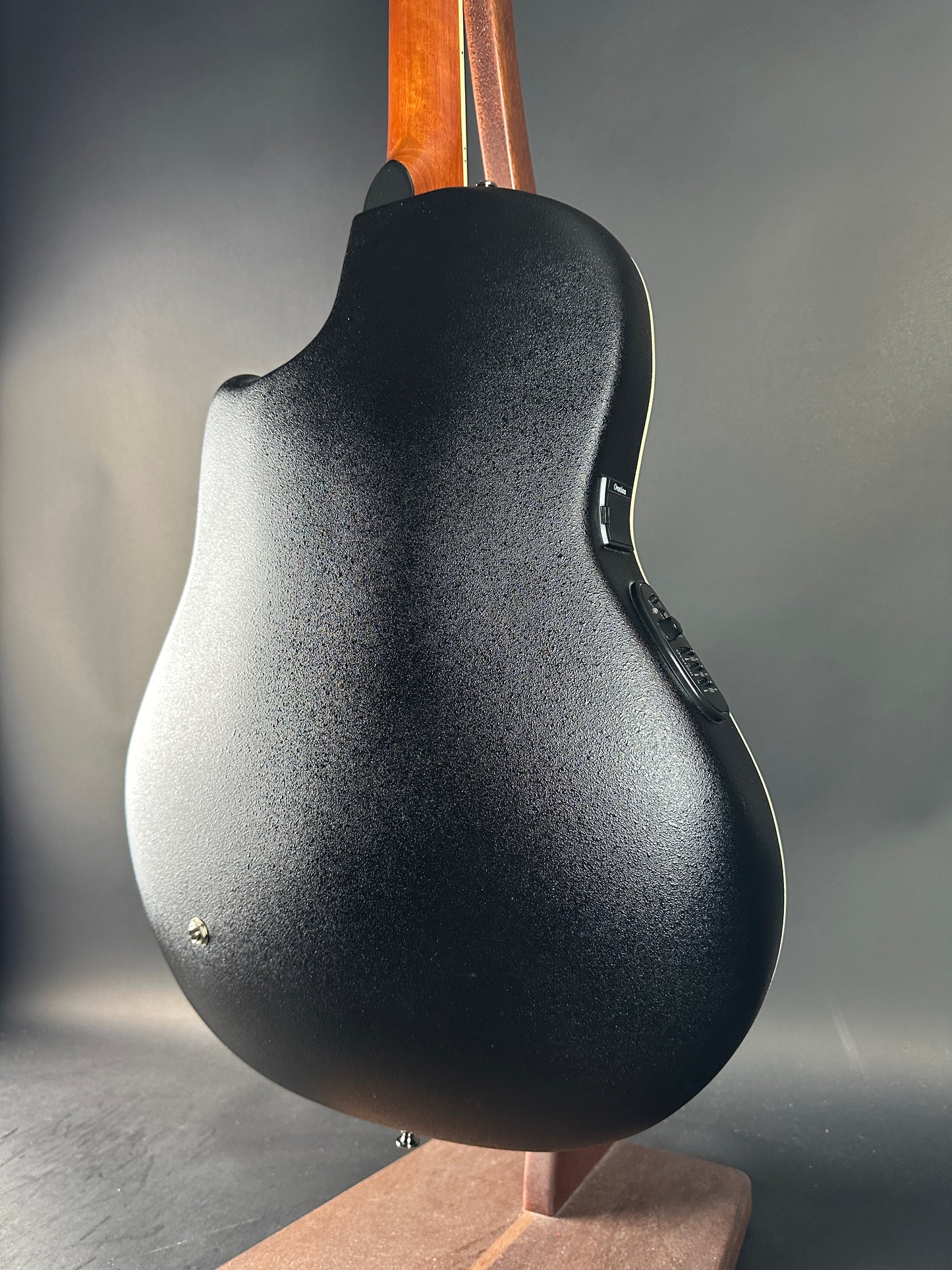 Close-up of a guitar body with a textured finish on a gray background