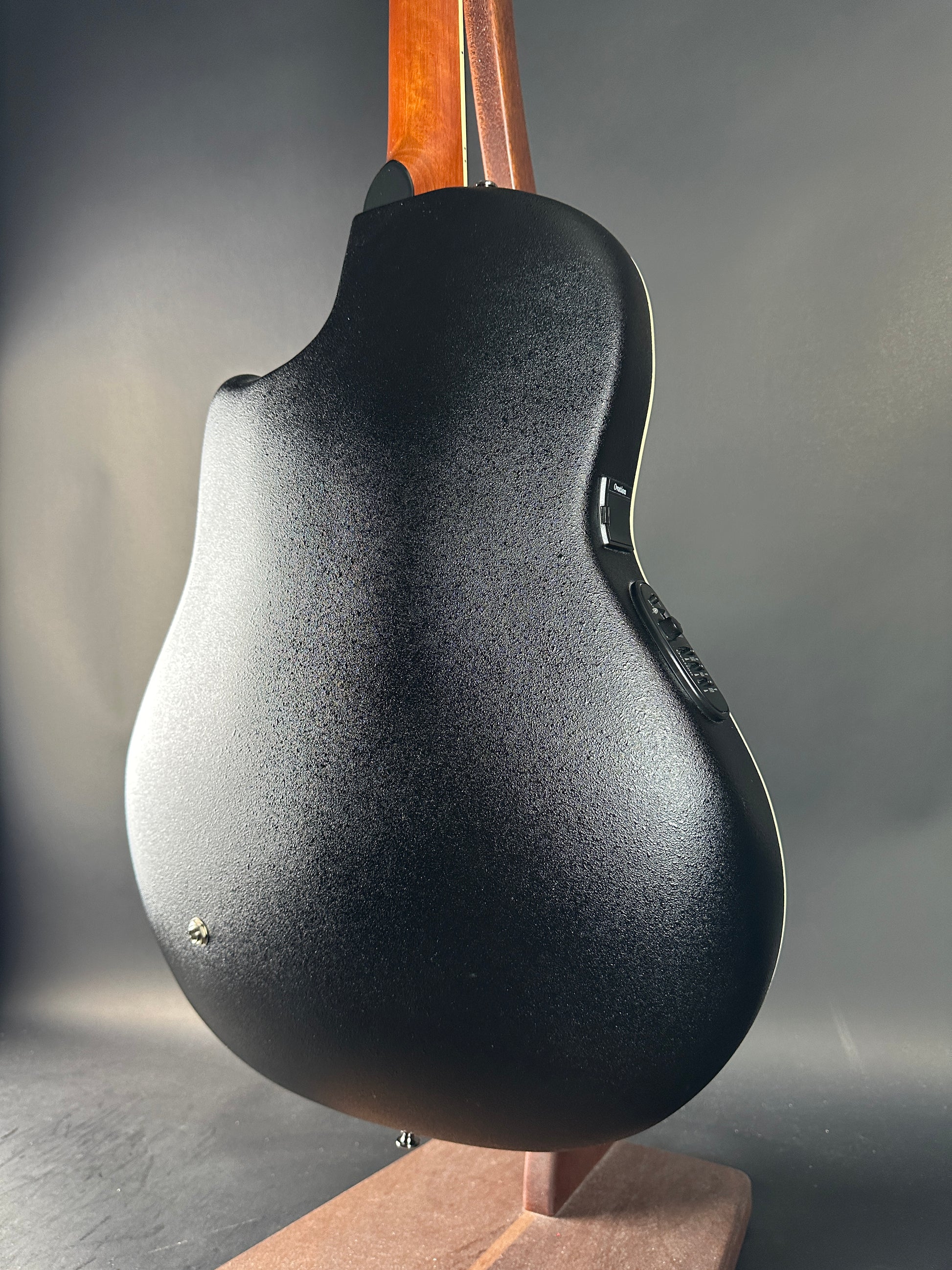 Close-up of a guitar body with a textured finish on a gray background