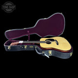 Acoustic guitar in an open case with 'Tone Shop' logo in the corner.