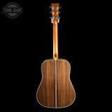Back view of a wooden acoustic guitar on a black background with 'Tone Shop' logo.