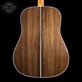 Back view of a wooden acoustic guitar with 'Tone Shop' logo.