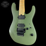An electric guitar with a matte sage green body, maple neck, and black hardware, shown against a solid black background with a Tone Shop watermark in the top left corner.