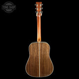 Back view of a wooden acoustic guitar on a black background with 'Tone Shop' logo.