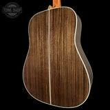 Close-up of a wooden acoustic guitar back with 'Tone Shop' logo.