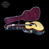 Acoustic guitar in an open case with 'Tone Shop' branding.