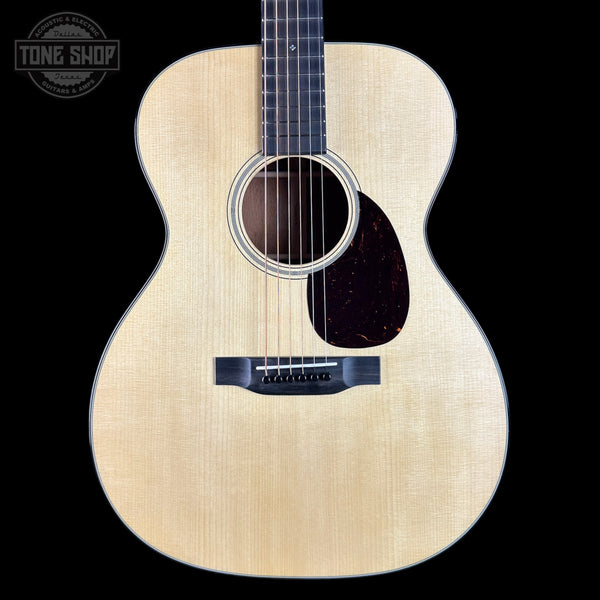 Acoustic guitar with a clear finish on a black background, featuring the Tone Shop logo.