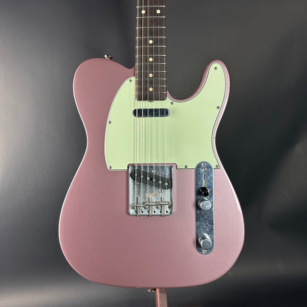 Pink electric guitar with a light green pickguard on a dark gray background