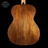 Back view of a wooden acoustic guitar with 'Tone Shop' logo.