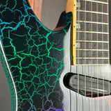 Close-up of an electric guitar body showing a black base with vivid green and blue lightning crackle pattern, alongside part of the fretboard and pickups.
