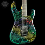 A custom electric guitar with a vibrant multicolor crackle pattern in green, yellow, blue, and red on a black base, shown against a solid black background with a Tone Shop watermark in the top-left corner.