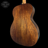 Close-up of a wooden acoustic guitar body with 'Tone Shop' logo.
