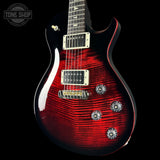 Electric guitar with a red and black design on a black background, featuring the Tone Shop logo.