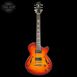 A double-cutaway electric guitar with a vibrant sunburst finish, featuring a black headstock and neck, photographed against a solid black background with a Tone Shop watermark in the top-left corner.