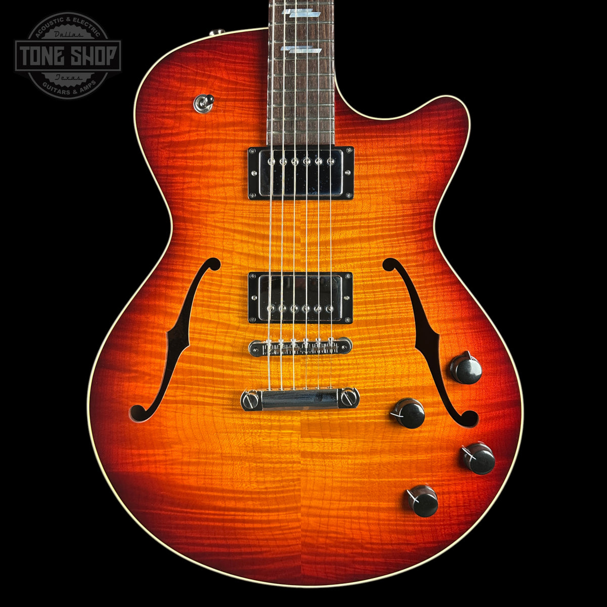 A double-cutaway electric guitar with a vibrant sunburst finish, featuring a natural wood grain pattern that transitions from bright orange to dark brown. The guitar is shown from the front against a solid black background, with a Tone Shop watermark in the upper left corner.