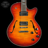 A double-cutaway electric guitar with a vibrant sunburst finish, featuring a natural wood grain pattern that transitions from bright orange to dark brown. The guitar is shown from the front against a solid black background, with a Tone Shop watermark in the upper left corner.