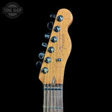 Close-up of a Fender electric guitar headstock in a natural wood finish with six black tuning pegs, shown against a solid black background with a Tone Shop watermark in the top left corner.