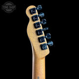 Close-up of the headstock of a guitar, showing a light natural wood finish and six black tuning pegs with visible Fender logos, set against a solid black background.