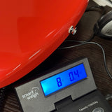 A close-up of a red motorcycle or scooter body panel resting on a digital scale displaying 8.04 kg.