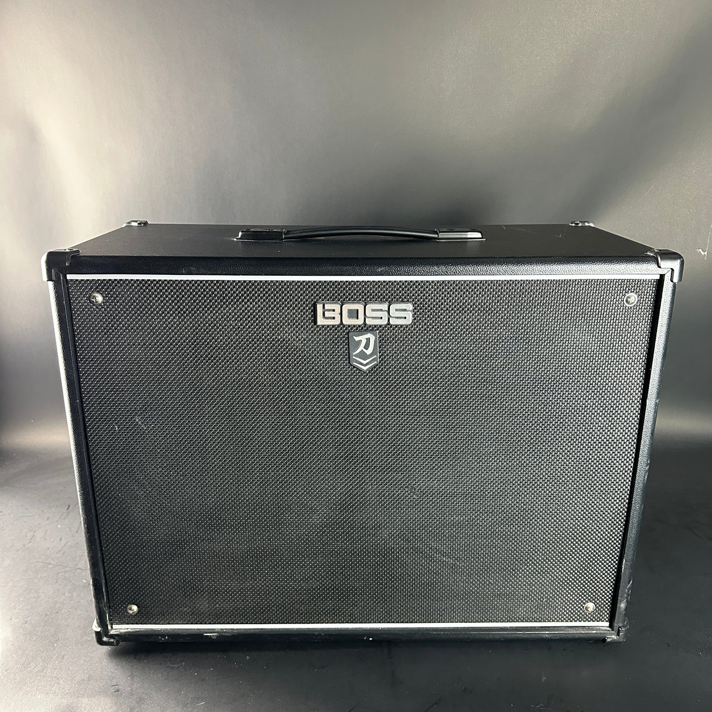 Black guitar amplifier with Boss logo on a gray background