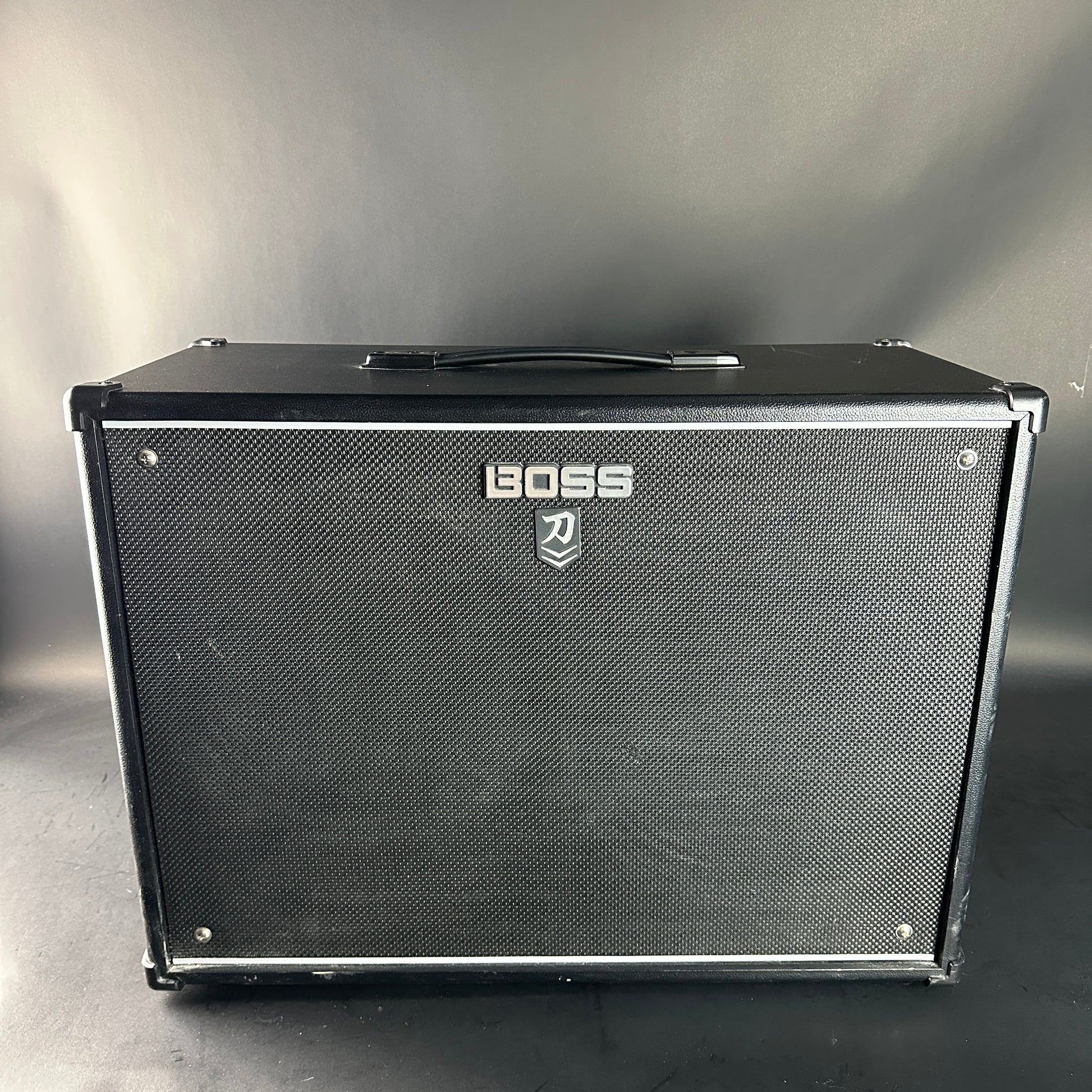 Black guitar amplifier with Boss logo on a gray background