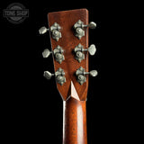 Close-up of the headstock of a wooden acoustic guitar, showing six metal tuning pegs on a black background with a Tone Shop watermark in the top left corner.